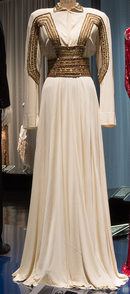 Off-white floor length evening dress with long sleeves and gold braid and square paillettes on …