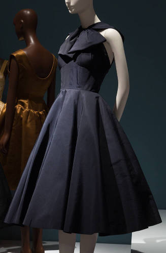 Navy blue cocktail dress with large bow at halter neckline, fitted waist and flared calf length…