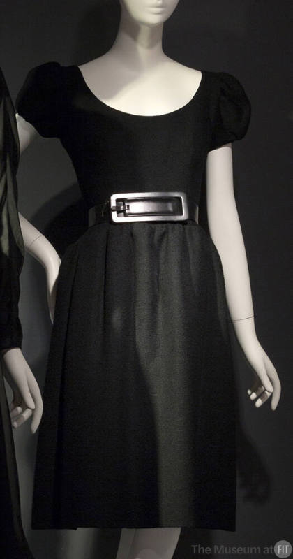 Black knee length dress with puffed cap sleeves and belt with large silver rectangular buckle 