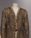 Detail view of top of gold and black brocade evening coat showing Oriental style patterns and g…