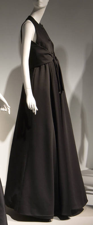 Side view of black sleeveless floor length evening dress with back bodice panel that ties at wa…