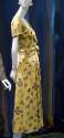 Side view of yellow dress printed with black bows with short sleeves, bodice bands tied into kn…