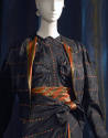 Detail view of black evening ensemble showing coral and gold striped jacket lining and matching…