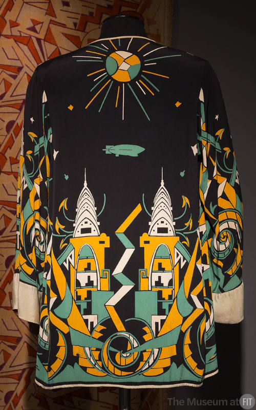 Back view of black jacket printed with Art Deco design of skyscrapers, sun and zeppelin in gold…
