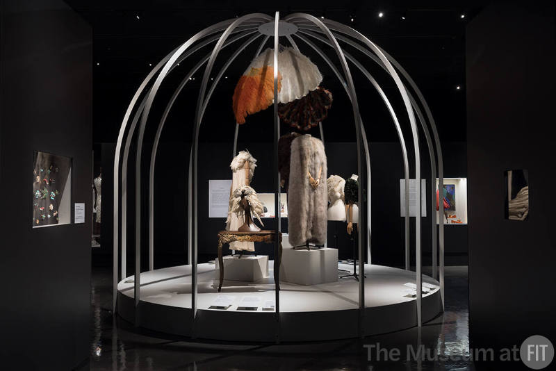 Fashioning Wonder exhibition installation view of dressed mannequins in a large bird cage surro…