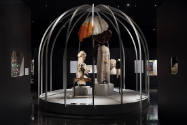 Fashioning Wonder exhibition installation view of dressed mannequins in a large bird cage surro…