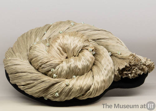 Pale green pleated dress accented with beads twisted and coiled in a spiral