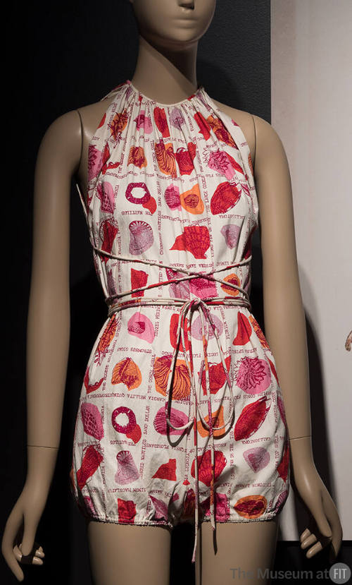 White halter neck romper style sunsuit with print of red, orange and purple seashells and tie w…