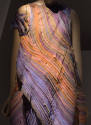 Detail view of evening dress showing layered strips in various shades of purple, yellow, orange…