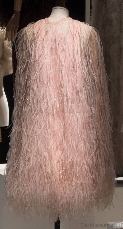 Rear view of sheer pink cape covered in pink feathers and iridescent sequins