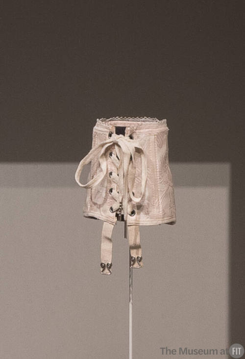 Pink patterned miniature sample corset with lacing through grommets and stretch garters at fron…