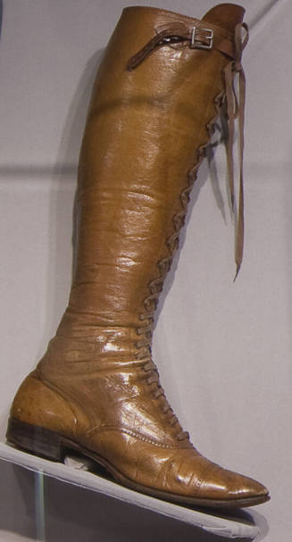 Brown knee length boot with stacked heel, pointed toe and center front lace closure
