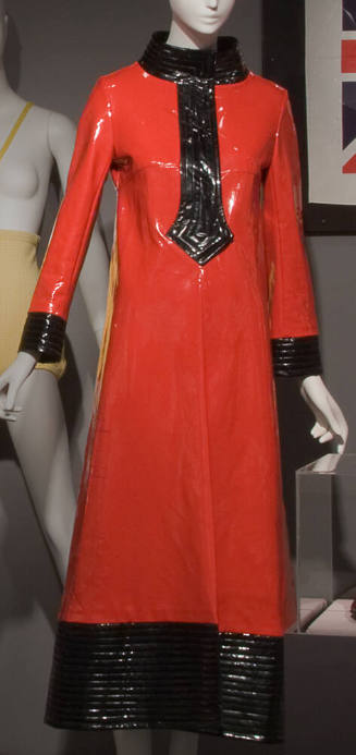 Red vinyl ankle length raincoat with black stand collar, stylized pointed placket, cuffs and he…