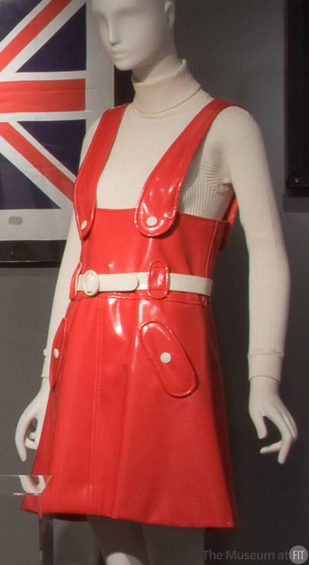 Red vinyl jumper mini dress with white belt, white buttons on wide shoulder straps and on hip p…