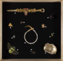 Fashioning Wonder exhibition installation view of a group of jewelry and accessories on a black…