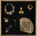 Fashioning Wonder exhibition installation view of a group of jewelry and accessories on a black…