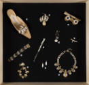 Fashioning Wonder exhibition installation view of a group of jewelry and accessories on a black…