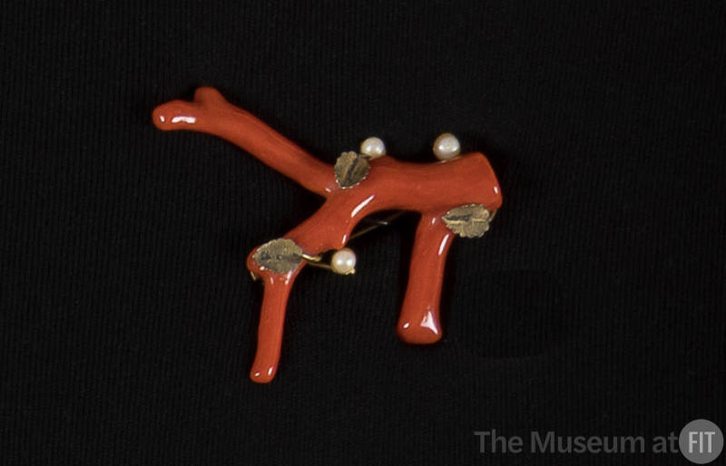 Brooch of a piece of red coral with three small pearls and gold leaves