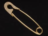 Gold ornament in the shape of a safety pin with rhinestone encrusted head