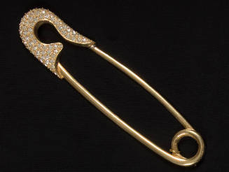 Gold ornament in the shape of a safety pin with rhinestone encrusted head
