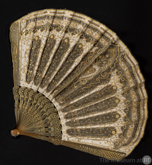 Gold metallic fan with floral design on amber frame and silk net and cream cut-out work embroid…