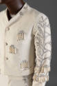 Detail view of man’s off-white collarless tuxedo jacket showing silver embroidery down arm and …