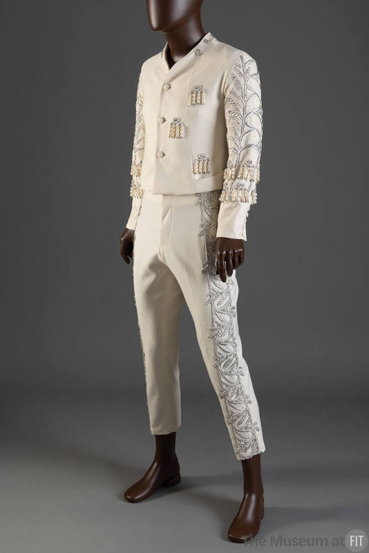 Man’s off-white tuxedo suit with silver embroidery in a leaf and vine pattern down arms and leg…