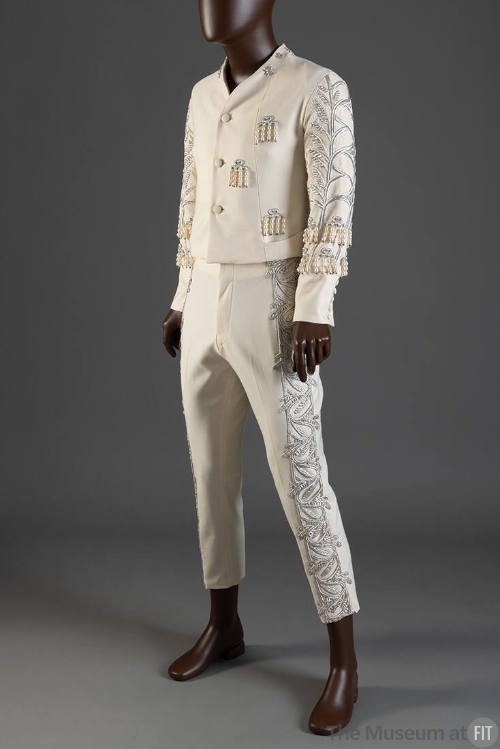 Man’s off-white tuxedo suit with silver embroidery in a leaf and vine pattern down arms and leg…