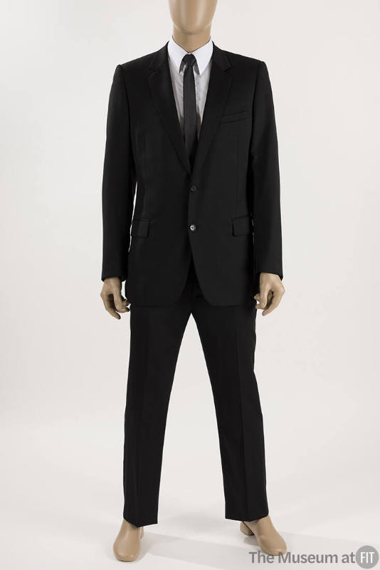 Man’s black two button suit with slim cut pants dressed with a white dress shirt and black tie