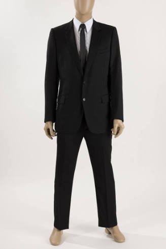 Man’s black two button suit with slim cut pants dressed with a white dress shirt and black tie