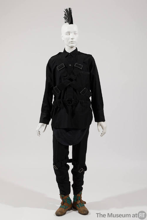Man’s ensemble of a black long sleeve shirt with multiple straps across front and on matching s…
