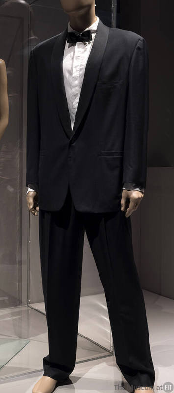 Man’s black tuxedo with satin shawl collar, tapered pants and white dress shirt dressed with bl…