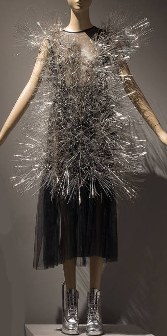 Black net below-the-knee dress with mini overdress of protruding steel needles and silver boots