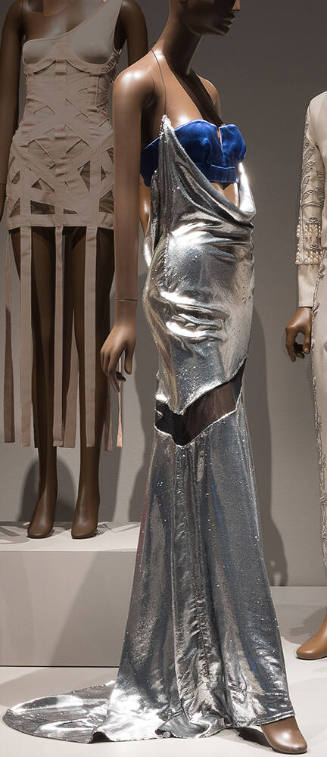 Floor length silver gown with spaghetti strap halter neck and cowl neckline plunging to waist t…