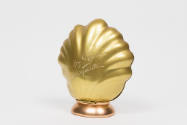 Gold shell shaped case with copper base and etched text on front: “Le Roy Soleil, Schiaparelli,…