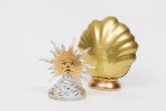 Glass perfume bottle in the shape of a gold sunburst rising over a mountain with a gold shell s…