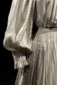 Detail view of off-white pinstriped dress showing puffed sleeve with smocking around gathered w…