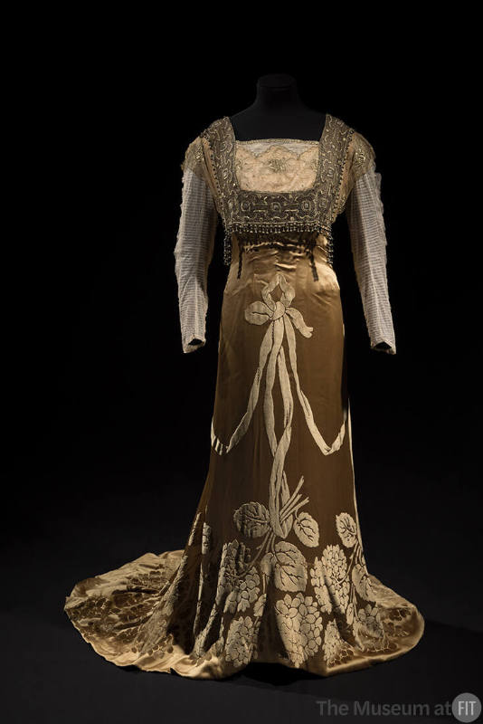 Light copper floor length dress with long net sleeves, square beaded panel over bodice and velv…