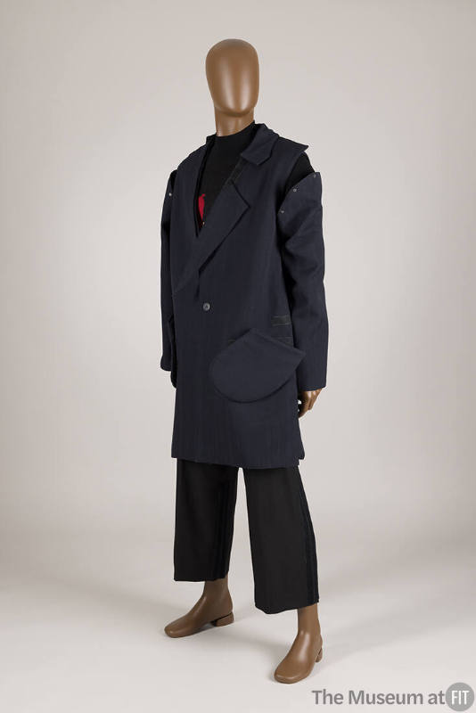 Man’s ensemble of navy blue deconstructed coat with detached sleeve over black sweater and crop…