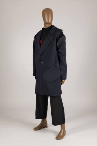Man’s ensemble of navy blue deconstructed coat with detached sleeve over black sweater and crop…