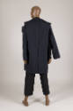 Back view of man’s navy blue jacket ensemble showing partially detached left sleeve and right a…