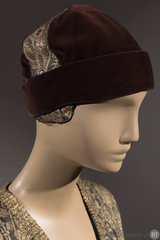 Brown velvet cloche hat with wide cuff brim and gold brocade ribbon trim across top from ear to…