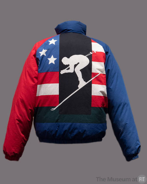 Back view of blue puffer ski jacket with stand collar, red left sleeve, red, white and blue Ame…