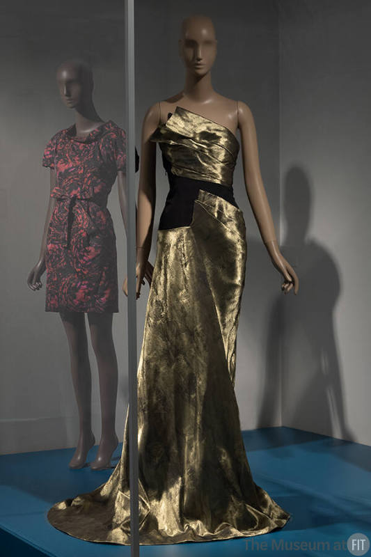 Gold strapless floor length pooling evening dress with asymmetrical bodice and draped skirt pan…