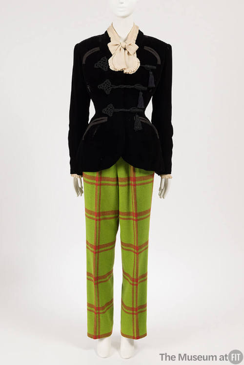 Black velvet jacket with braid frog closures and tassels over cream blouse with bow tied collar…