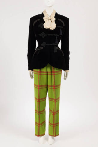 Black velvet jacket with braid frog closures and tassels over cream blouse with bow tied collar…