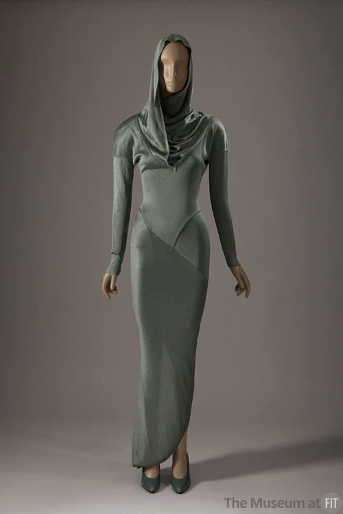 Green ankle length long sleeve sheath dress with hood, cowl neck and seams across forearms and …