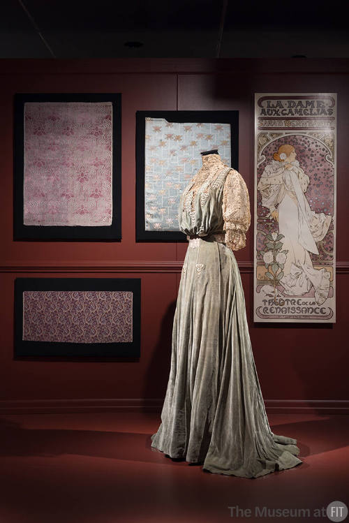 Art X Fashion exhibition installation view of a mannequin in a dress in front of an image of a …