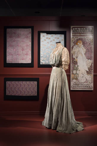 Art X Fashion exhibition installation view of a mannequin in a dress in front of an image of a …