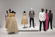 Art X Fashion exhibition installation view of eight dressed mannequins on a white platform